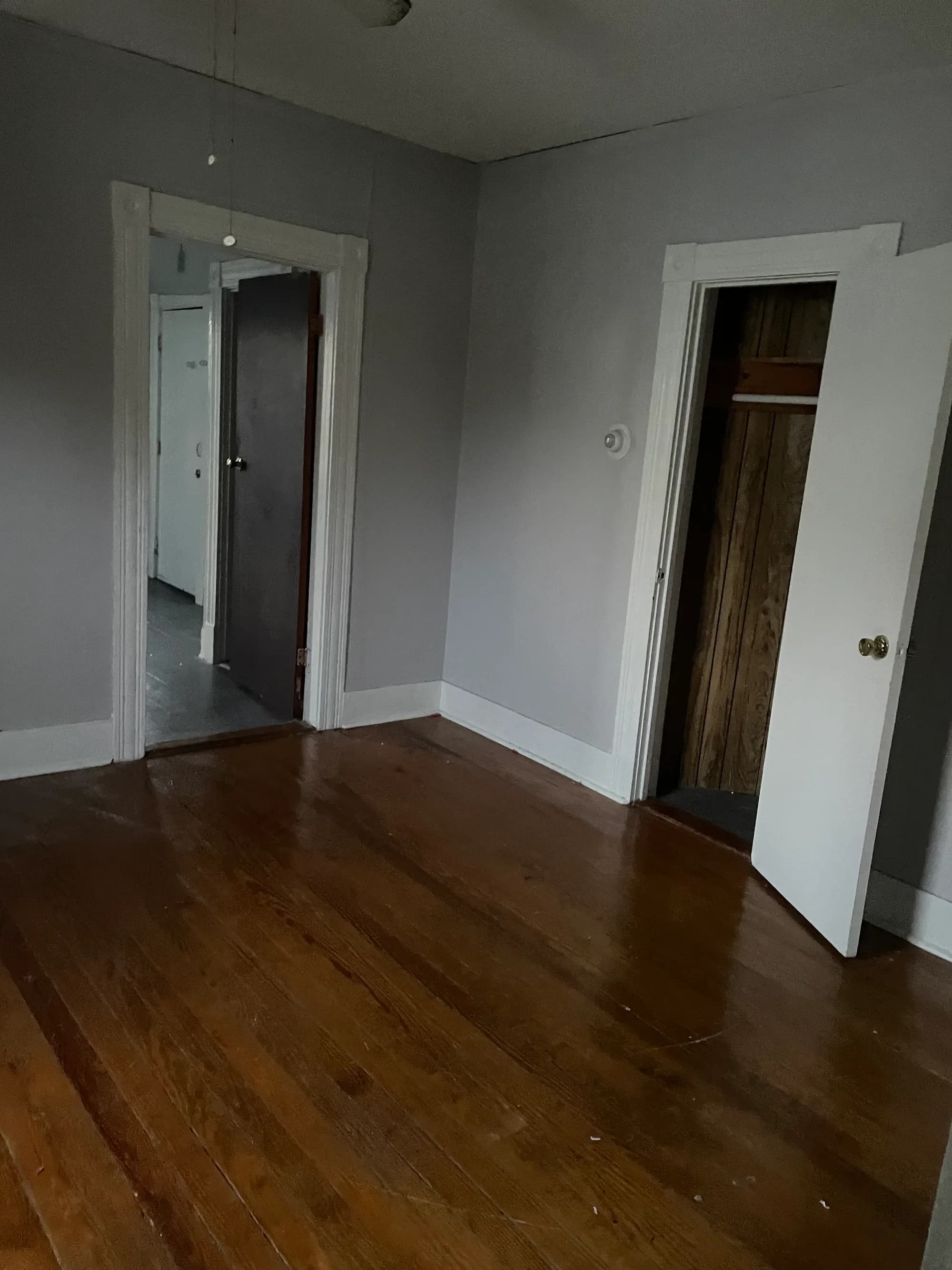A cleared room with open doorways and a swept wood floor, prepared for sale.