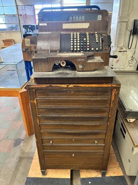 An antique hand-crank cast-iron machine on a metal stand.
