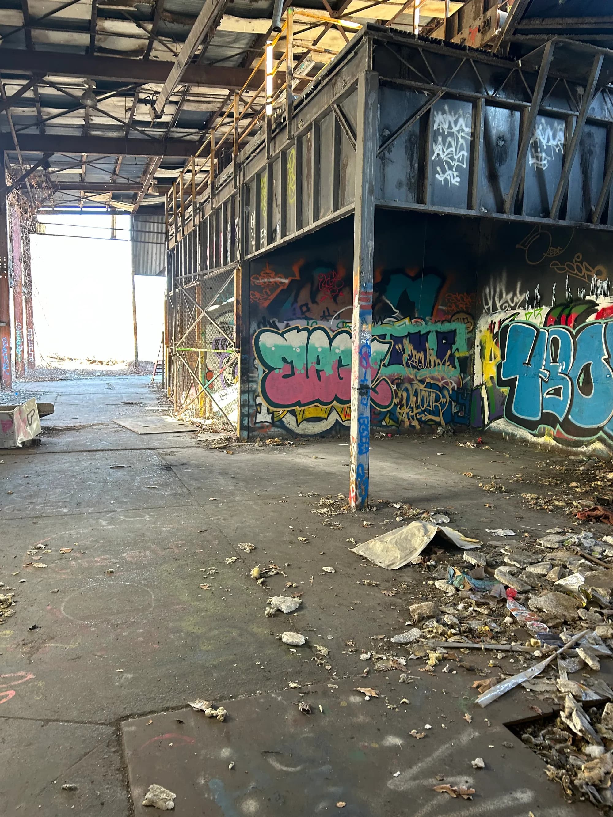 A graffiti-covered, debris-strewn industrial interior before clearing.